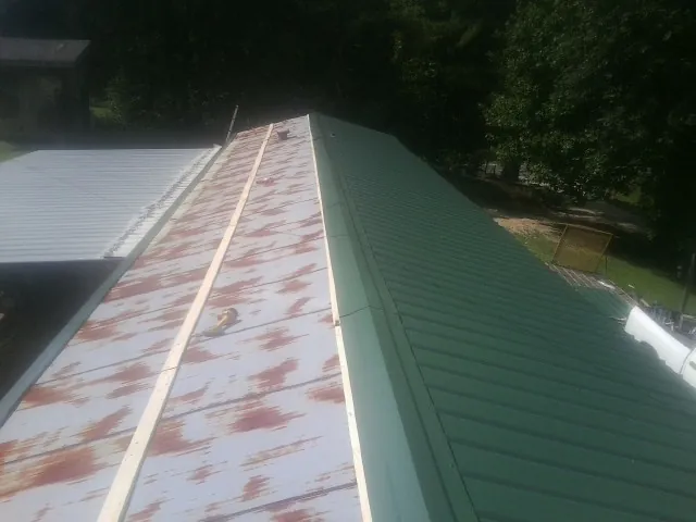 Old rusted panels beside newly installed green metal roofing — Wind Damage Roof Repair by Roofing Brothers in Middleburg
